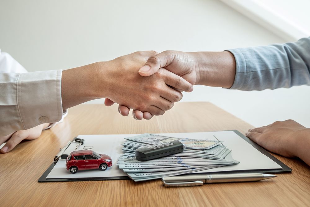 Lease Agreements Image of a handshake as a car dealership provides advice about insurance details, featuring 411 Real Estate Law and highlighting 'Lease Agreements,' ensuring it aligns with the page's context.